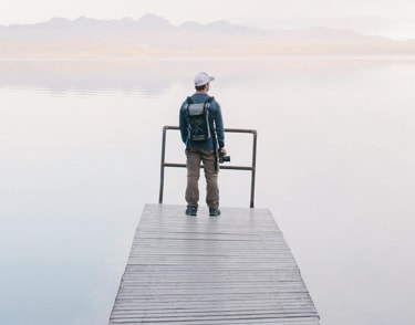 An image of a person standing by a lake looking at the horizon
