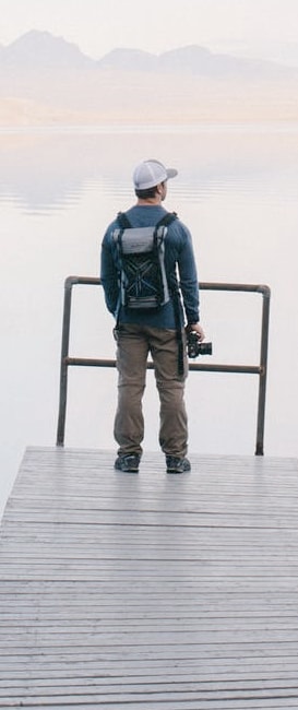 An image of a person standing by a lake looking at the horizon